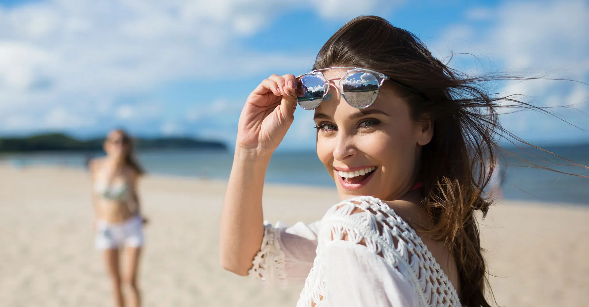 A woman wearing sunglasses on the beach.