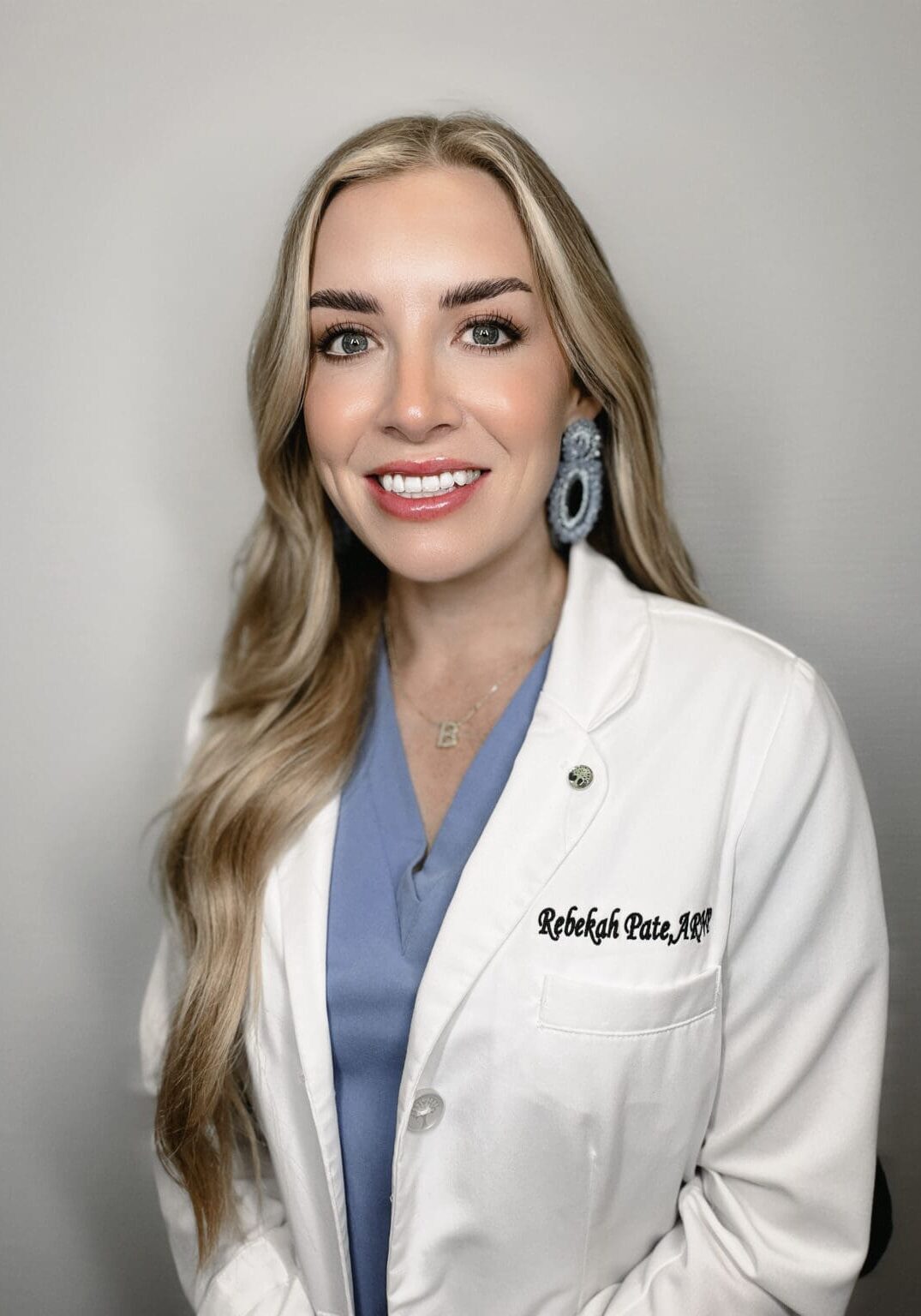 A woman in white lab coat and blue shirt.